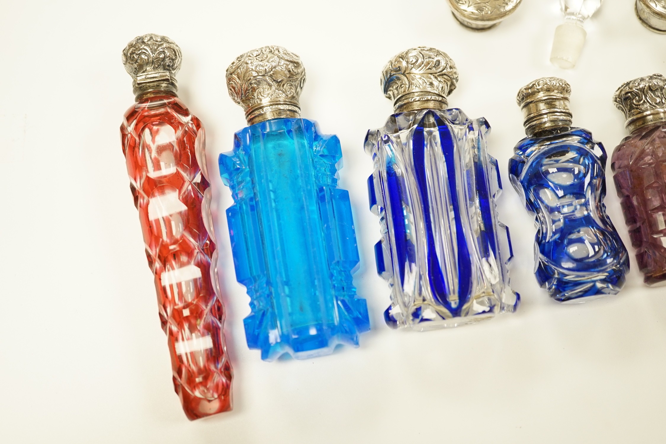 A late Victorian silver mounted cut glass scent bottle, Charles Boyton II, London, 1896, 82mm and six other late 19th/early 20th century, silver or white metal mounted coloured cut glass scent bottles (some a.f.) and two